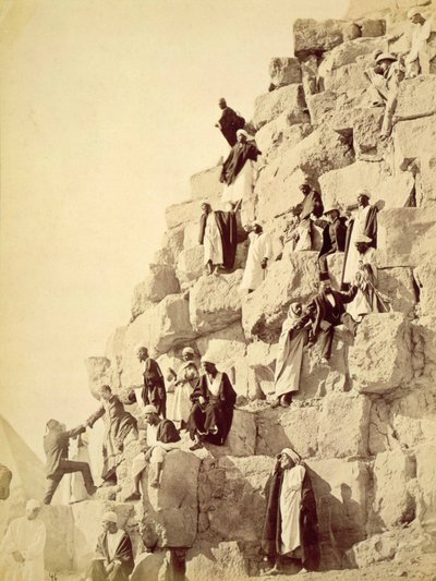 Arabs assisting tourists to climb the pyramids at Giza (sepia photograph) by Unknown
